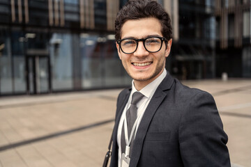 Portrait of a businessman with glasses goes to work in the office in a business suit, smiles and thinks about the project.