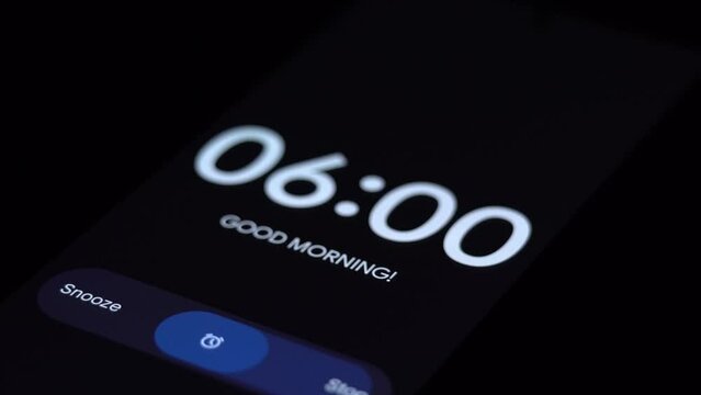 Good morning 6 am alarm clock on the phone, a finger taps stop. Close-up Focus on Mobile Phone Clock Showing Six A.M