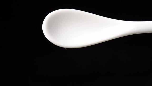 Dried cumin spice seeds on a spoon is poured out isolated on a black background. Dry seasoning in spoon. Spices and herbs for cooking zira