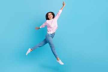 Full length photo of positive excited lady wear striped sweater jumping high rising fists empty space isolated blue color background