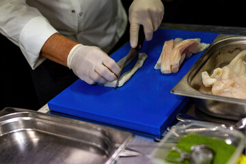 The cook is chopping the sole. Cutting the fish with a knife.