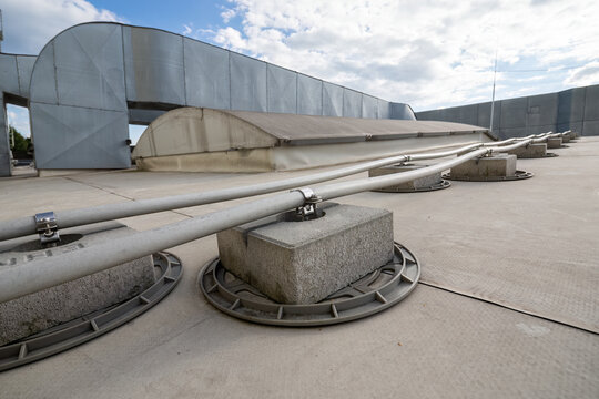 Insulated lightning conductor leads held in concrete footings on the roof and HVAC in the background.