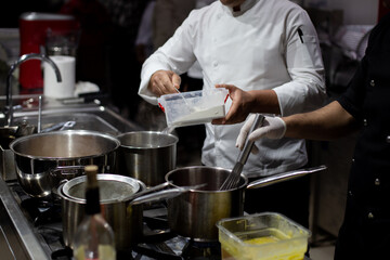 The cook pours the vegetables from the cutting board into the pot. The cook is cooking.