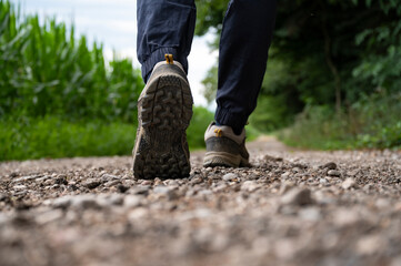 Low angle view of a sole of a man in hiking shoes walking on a gravel road - 554519504