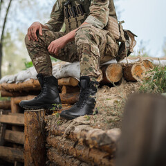 Fototapeta premium A military soldier in a special uniform with a tactical backpack near a trench