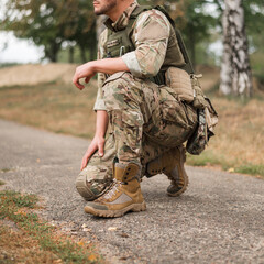 A military soldier in a special uniform with a tactical backpack on the battlefield