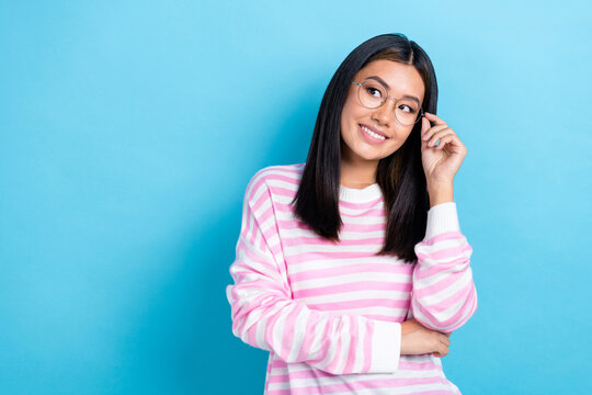 Photo of adorable dreamy girl dressed pink pullover arm eyewear smiling looking empty space isolated blue color background