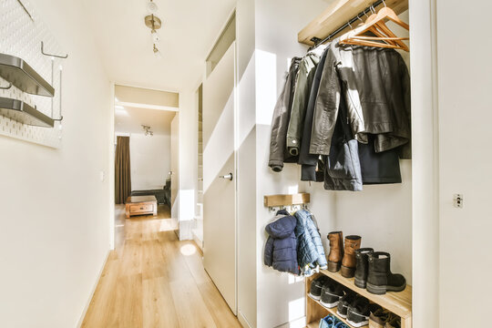 A Walk - In Closet With Clothes Hanging On The Wall And Coat Rack Holding Coats, Shoes And Other Items