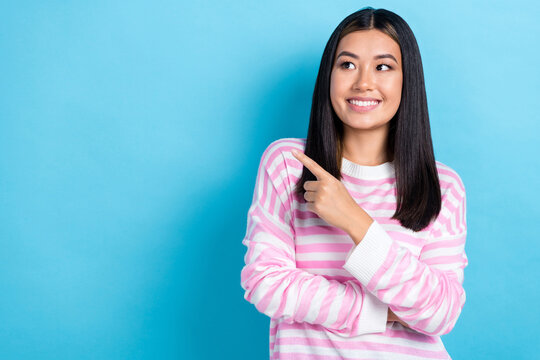 Photo of dreamy positive young lady wear striped sweater pointing finger looking empty space isolated blue color background