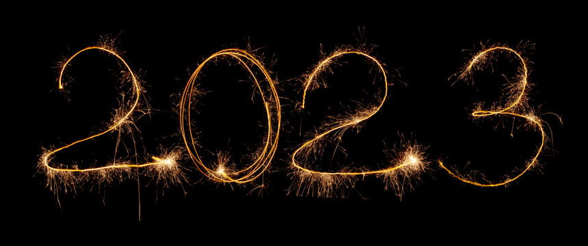 2023 inscription of numbers from sparklers and sparks on a black background. Isolated sparks of New Year's fireworks in the dark.