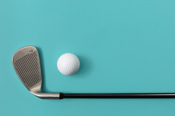 Golf club and golf ball isolated on light turquoise green background. Space for text.