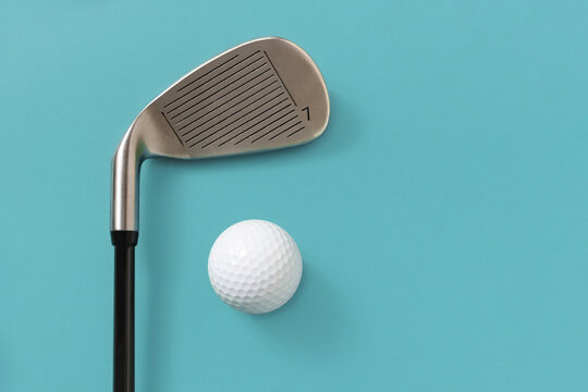 Detail of golf club and golf ball isolated on light turquoise blue background. Space for text.