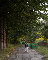 A little boy runs to the camera in the park. a beautiful child walks along the path in the park.