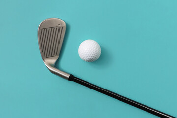 Golf club and golf ball isolated on light turquoise blue background. Concept of sport. Space for text.