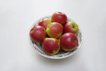 Red apples in a plate on a white background. Still life. Close-up. Selective focus with copy space.