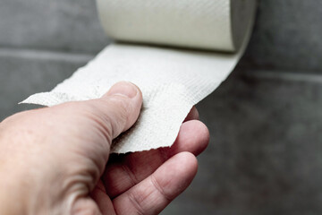 A man tears off a piece of toilet paper from a roll