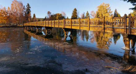 Wide angle view of the Drake Park bridge overlooking the Mirror Pond in Bend, Oregon, on a beautiful late autumn blue sky afternoon.