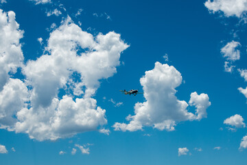 puffy clouds with plane flying by