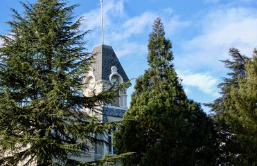 Benton Hall clock tower at Oregon State University in Corvallis, Oregon with evergreens and blue sky