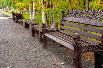 City brown wooden bench on the street in the autumn park