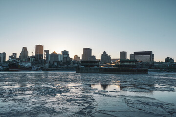 Panomaric view of boats floating on ice cold river in Montreal Old Port City skyline skyscraper at sunset during winter cold season day hour