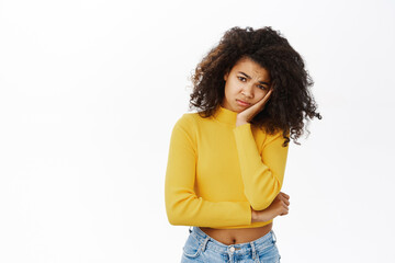 Portrait of teen black girl, student looking lonely or sad, upset, sulking and frowning disappointed, standing over white background