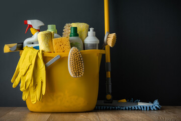 Brushes, bottles with cleaning liquids, sponges, rag and yellow rubber gloves on the black...