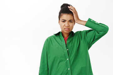 Portrait of concerned Black girl, holds hand on head complicated, confused and puzzled by smth,...
