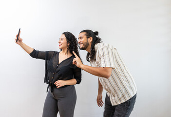 Cheerful lovely latin couple making self photo, showing v-sign