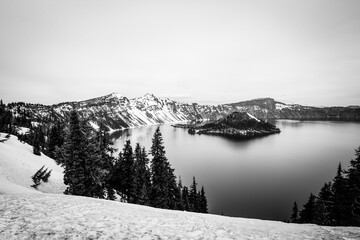 Snow-covered mountains stretch above the famous Crater Lake in Oregon, with Wizard Island prominently displayed