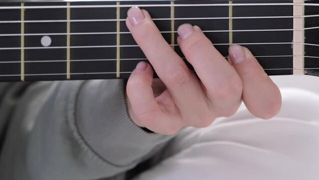 hands close up, girl pinches chords with her fingers, playing acoustic classic guitar, singing song and relaxing at home