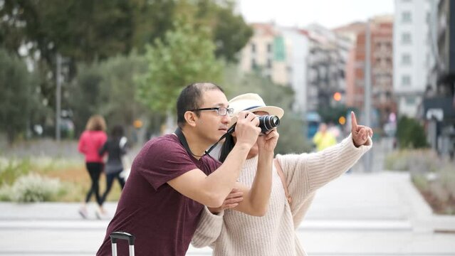 Multi-ethnic traveler couple pointing and taking photos in city together. Sightseeing in Madrid, Spain.