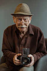 An old photographer with a medium format film camera in his hands.