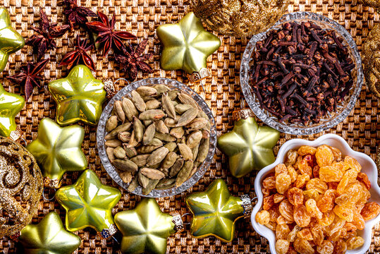 Golden raisins, cardamom and cloves with Christmas tree decorations on a yellow background