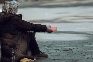A beggar sits on the street - obrazy, fototapety, plakaty