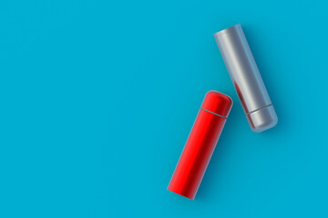 Thermoses on blue background. Metallic thermo flasks. Space for text. Top view. 3d rendering