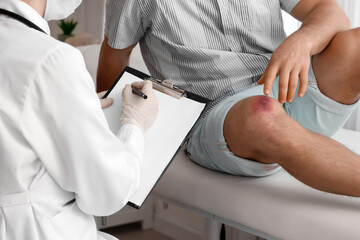 Doctor examining man with bruises in clinic
