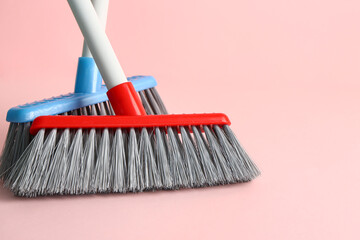 Cleaning brooms on pink background, closeup