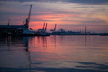 Obraz premium sunset in industrial landscape of commercial seaport. Sunset at seaport.