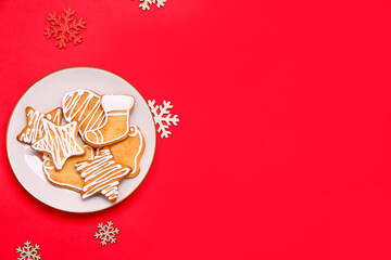 Plate with tasty Christmas cookies and decorations on red background