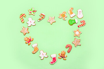 Heart made of tasty Christmas cookies on green background