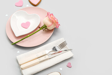 Table setting for Valentine's Day with pink rose on grey background