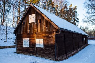 Old building in winter time with snow hit by setting sun light in Hembygdsparken in Hässleholm, Scania, Sweden.