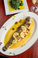 Grilled Fish. Branzino, whole grilled sea bream. Classic regional Greek  seafood favorite. Whole fish, grilled with skin in, served with lemon potatoes lemons Italian parsley and capers.