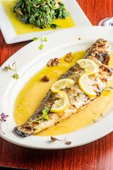 Grilled Fish. Branzino, whole grilled sea bream. Classic regional Greek  seafood favorite. Whole fish, grilled with skin in, served with lemon potatoes lemons Italian parsley and capers.