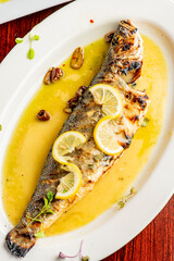 Grilled Fish. Branzino, whole grilled sea bream. Classic regional Greek  seafood favorite. Whole fish, grilled with skin in, served with lemon potatoes lemons Italian parsley and capers.
