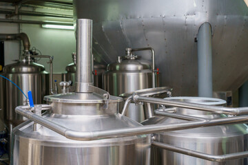A stainless steel vat in the food industry at a brewery in the process of brewing beer. Background