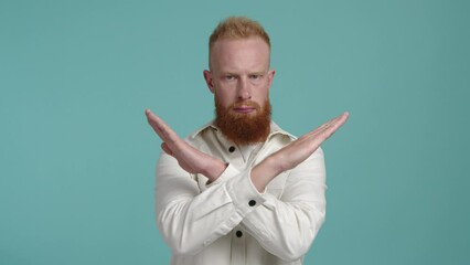 Close-up shot of caucasian, red-haired male model feeling concerned. Adult guy crossing his arms to stop something. High quality 4k footage