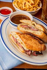 Reuben Sandwich. Classic traditional American sandwich. Pastrami and corned beef on grilled rye bread, melted Swiss cheese, sauerkraut, topped with thousand island dressing served french fries.