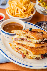 Reuben Sandwich. Classic traditional American sandwich. Pastrami and corned beef on grilled rye bread, melted Swiss cheese, sauerkraut, topped with thousand island dressing served french fries.